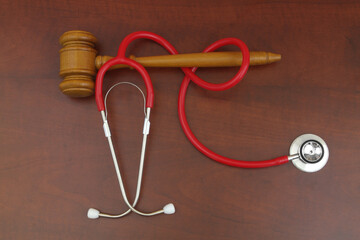 Wooden gavel with red stethoscope on table. Medical mistake concept.