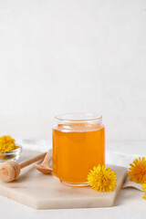 Board with jar of dandelion honey on white table