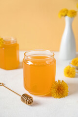 Jars with dandelion honey on white table