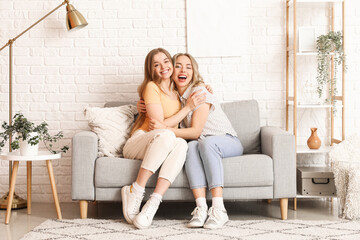 Young sisters hugging on sofa at home