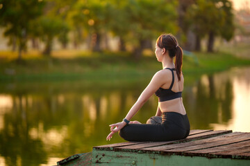 Asian woman in sportswear practises yoga at sunrise pose nature outdoors