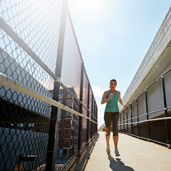 I never skip a run. a sporty young woman running on a footbridge.