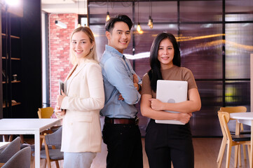 business team standing smiling and holding a laptop.