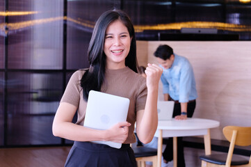 smiling business woman Standing holding a laptop inside the office.