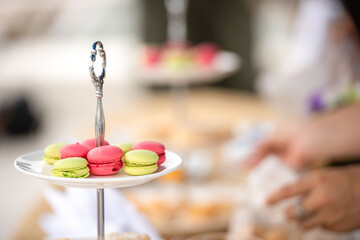 Afternoon tea stand decorate catering banquet table services with macaroon snacks and appetizers, fresh fruits on bartender counter in hotel restaurant. Snack foods serving in party event.