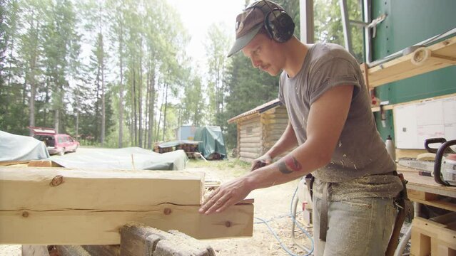 Profile shot of caucasian craftsman removing piece out of wood log with axe