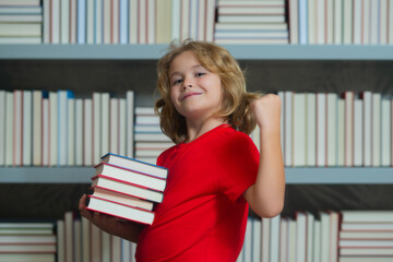 Successful school kid. School child pupil reading book at school. Kid doing homework, sitting at table by books, in classroom.