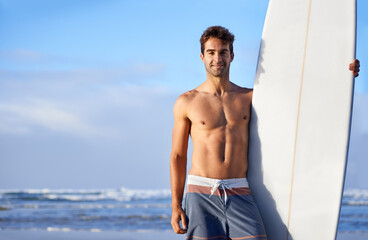 Obraz premium Chasing waves is his passion. A handsome young surfer at the beach craving a good wave.