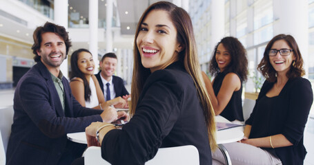 Everybodys welcome. a young businesswoman smiling in an office during a meeting with her colleagues...