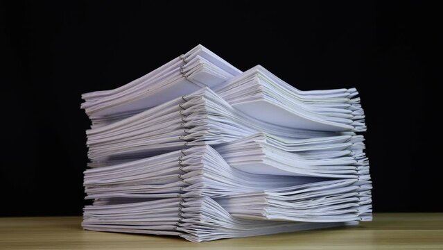 stack of paper documents with clip on a wooden table. Corporate business financial data management concept. Organize Documents &ndash; 4K Stop Motion, Stack Files Overload