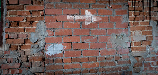 Grunge vintage brick wall with white arrow drawn on it. Industrial background. Banner. Copy space.