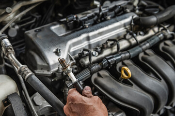 Auto mechanic checking an old spark plugs from the engine.