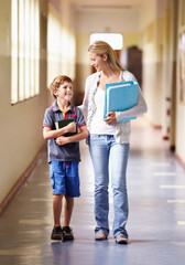 Teacher, child and walking in corridor at school, talking and bonding together. Education, smile and woman walk with kid, boy or student in hallway while going to class, speaking and discussion.