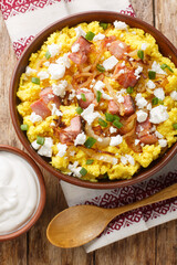 Typical Ukrainian dish polenta Banosh with onion, cracklings and cheese closeup on the bowl on the wooden table. Vertical top view from above