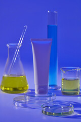 Laboratory filled with blue and yellow fluid decorated with a white tube standing on round podium. Mockup of skin care cosmetic tube of beauty facial