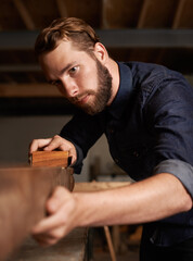 Carpenter, wood sanding and man working on building construction and architecture project. Home improvement, maintenance and handyman work of a young male employee with carpentry tool for woodwork