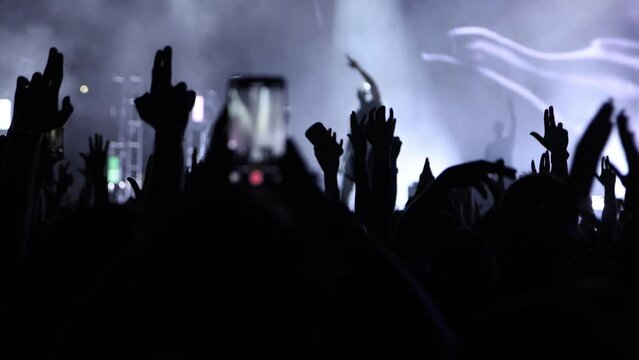 Silhouettes of Fans Hands Making Symbolic Signs on Live Concert with Singer Performing on Stage