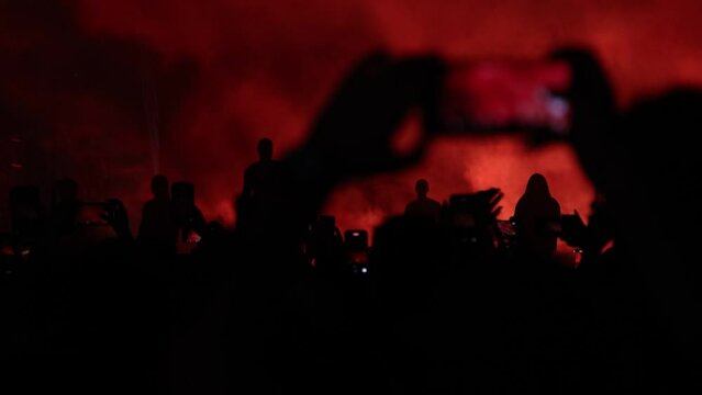 Fans Filming Live Performance of Singer on Illuminated Stage Using Smartphones Amidst Vibrant Lights