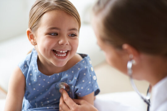 Happy girl, kid and pediatrician with stethoscope for medical consulting, healthy lungs and listening to heartbeat. Face of child, doctor and chest assessment, healthcare analysis and smile in clinic