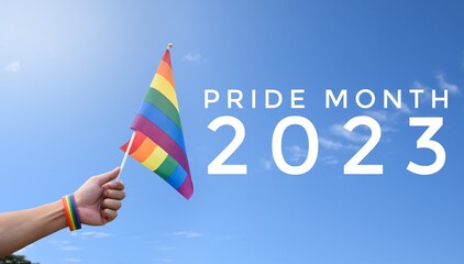 'Pride Month 2023' on blurred rainbow flag raising background, concept for LGBT people celebrations...