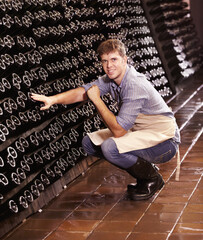 Portrait, man and counting bottles of wine in cellar, warehouse or factory. Alcohol, manufacturing...