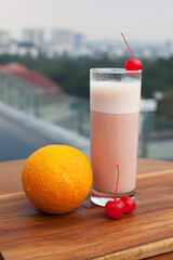 Close Up Mixed Smoothies. Orange and Strawberry is the ingredients. Served with ice and cherry sliced on the top of glass. Pool view. This smoothies suitable for summer beverage