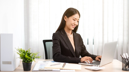 Smart business woman is sitting at workplace and using computer.