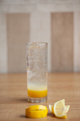 Lemon juice or lemonade with yellow limon sliced isolated on wooden table background. Copy space.