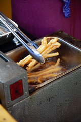 Delicious French fries are taken out from hot oil.