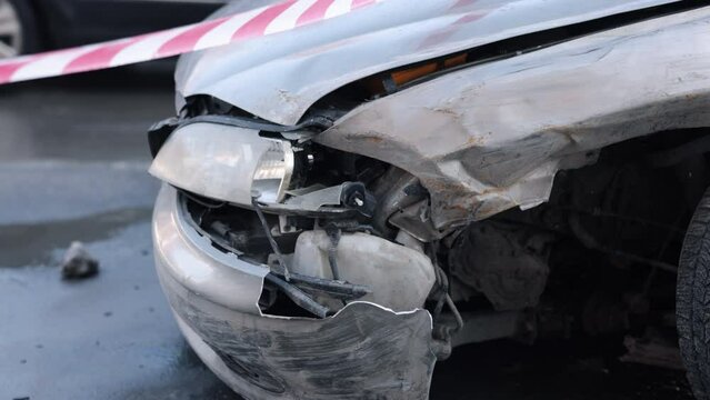 Accident aftermath, collision damage, car wreck. With heavily damaged front from accident, automobile marked off by caution tape.