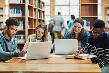 Staying fully engaged in their education. a group of university students working in the library at...
