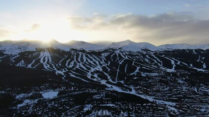Aerial Cinematic drone view of Breckenridge Ski area and town from Boreas Pass late afternoon sunset over mountain tops mid winter pan to the right