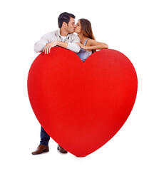 Be mine forever and a day. Studio shot of a couple kissing while standing behind a large heart isolated on white.