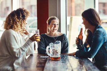 Friends make every hour a happy hour. a group of friends enjoying some beers at a bar.