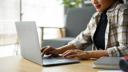 Cropped image of smiling creative woman using laptop, working on design project at home