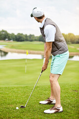 Fototapeta premium Lining up the shot. Full length shot of a handsome young man playing a round of golf on a golf course.