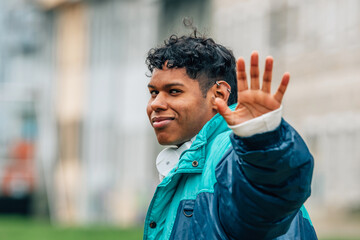 young latino man waving in the street
