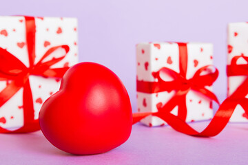 gift box with red bow and red heart on colored background. Perspective view. Flat lay