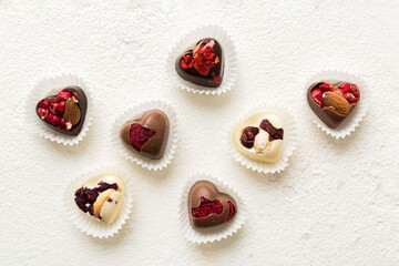 chocolate sweets in the form of a heart with fruits and nuts on a colored background. top view with space for text, holiday concept