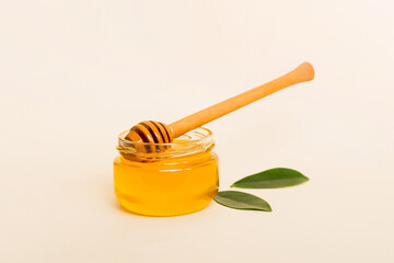 Honey in jar with leaves and honey dipper on colored background top view with copy text