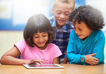 Learning the ABCs of technology. elementary school children using a digital tablet while sitting in class.