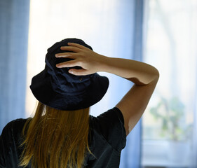 Kobieta w kapeluszu z ręką na głowie  - obrazy, fototapety, plakaty