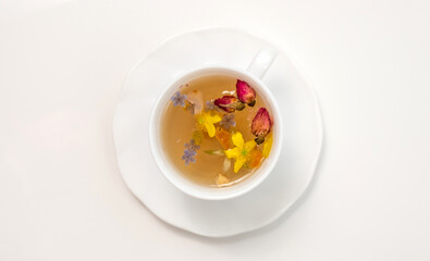 A white cup with fragrant herbal tea and flowers is the perfect choice for health and wellness. Tea time. Relaxing with herbal tea, white background, top view, vertical
