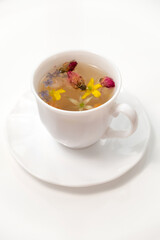 Fototapeta na wymiar A white cup with fragrant herbal tea and flowers is the perfect choice for health and wellness. Tea time. Relaxing with herbal tea, white background, top view, vertical