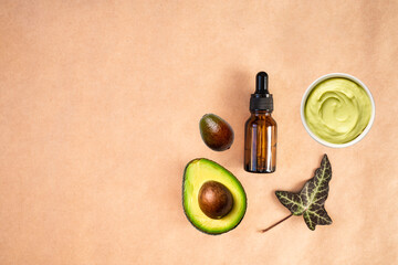 Obraz na płótnie Canvas Avocado essential oil dropper and avocado mask on a beige background. Flat lay, top view, copy space.
