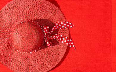 Top view of red summer hat on the red beach towel.Empty space