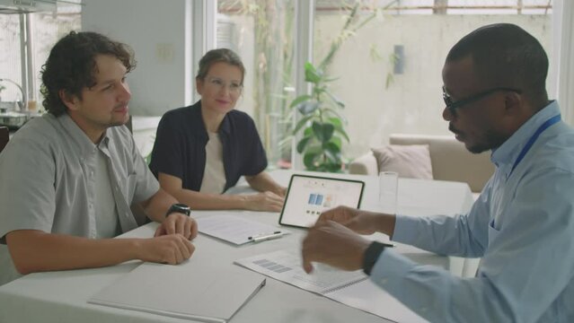 African American sales representative telling about engineering solutions to family couple while having business meeting in office of sustainable energy company