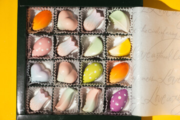Close up of homemade multicolored chocolate bonbons in a gift box. Assortment of hand painted candies. Flat lay. Macro shot of chocolatier products