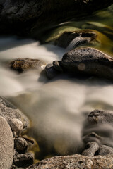Fototapeta premium Torrente di montagna in luce diurna fotografato con esposizione lunga, effetto mosso dell'acqua che scorre velocemente