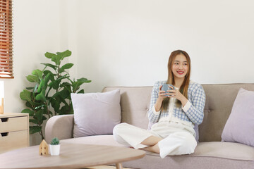 Fototapeta premium Rest time concept, Women sitting on comfortable couch and holding coffee cup to spending relax time